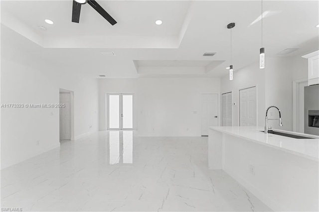 interior space featuring white cabinetry, a tray ceiling, ceiling fan, and open floor plan