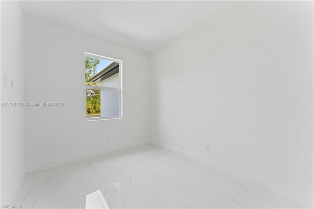 spare room with marble finish floor and baseboards