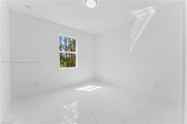 unfurnished room featuring marble finish floor and baseboards