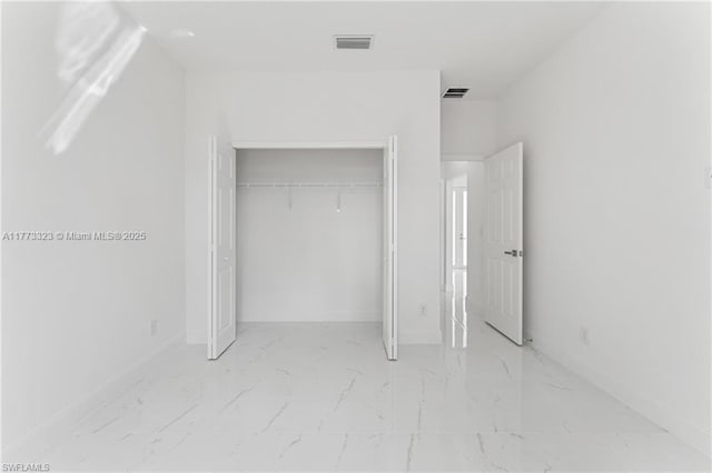 unfurnished bedroom featuring marble finish floor, baseboards, visible vents, and a closet