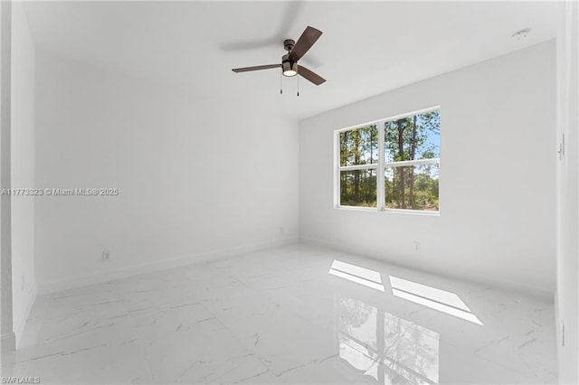 empty room featuring marble finish floor, baseboards, and ceiling fan