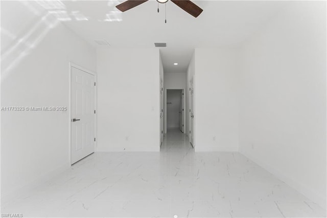 empty room with marble finish floor, baseboards, visible vents, and a ceiling fan
