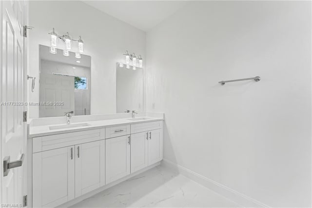 bathroom featuring marble finish floor, a sink, double vanity, and baseboards