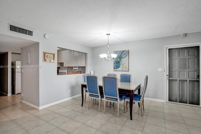 dining area with light tile patterned floors, baseboards, a chandelier, a textured ceiling, and visible vents