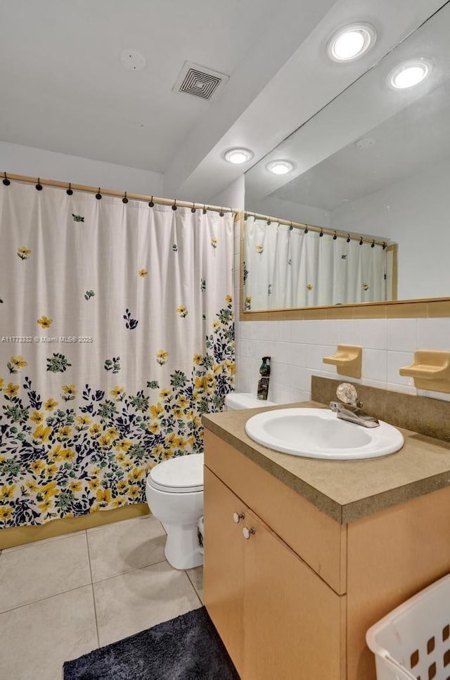 bathroom with toilet, vanity, backsplash, tile patterned flooring, and visible vents