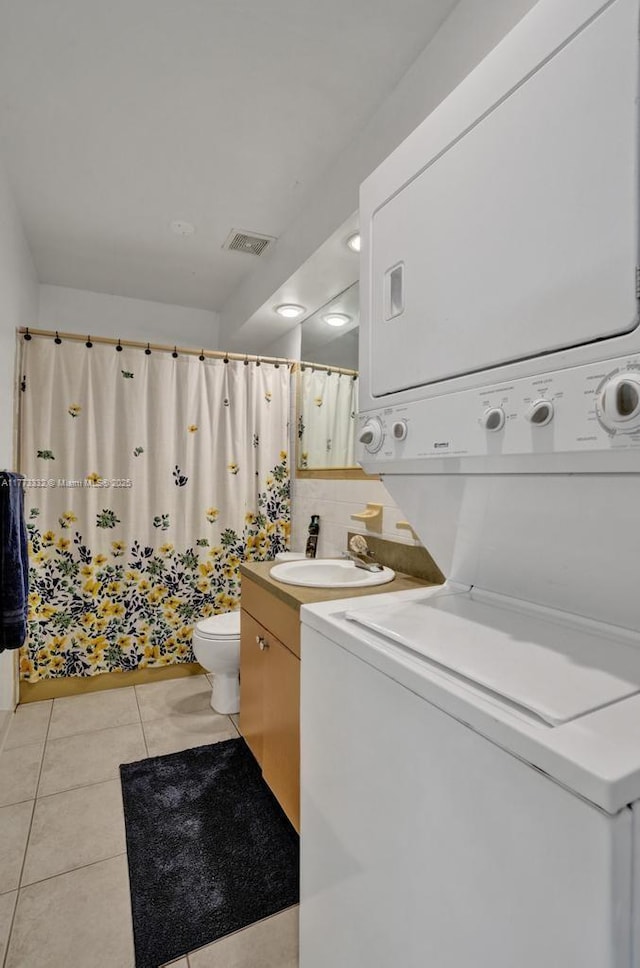 bathroom featuring stacked washer and dryer, visible vents, toilet, and tile patterned flooring