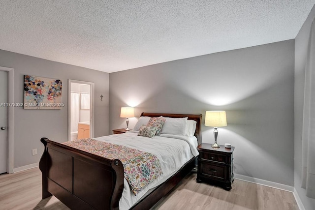 bedroom with light wood finished floors, baseboards, and a textured ceiling