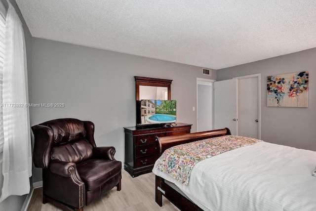 bedroom featuring a textured ceiling, light wood-style floors, and visible vents