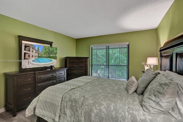 bedroom with a textured ceiling, wood finished floors, and access to exterior