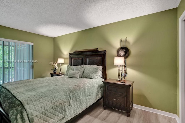 bedroom featuring baseboards, a textured ceiling, light wood-style flooring, and access to outside