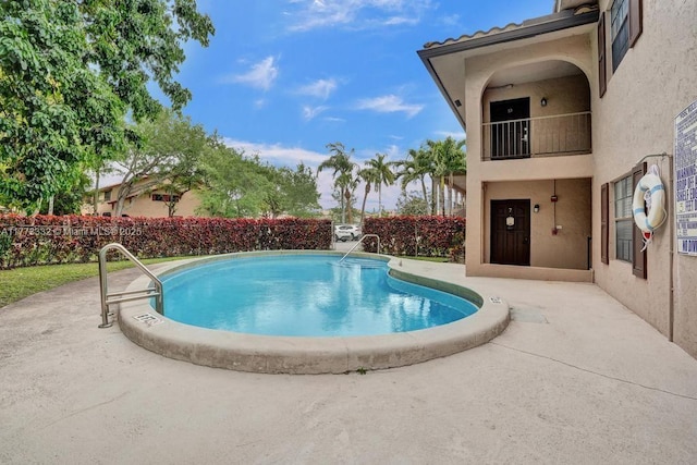 community pool with a fenced backyard and a patio area