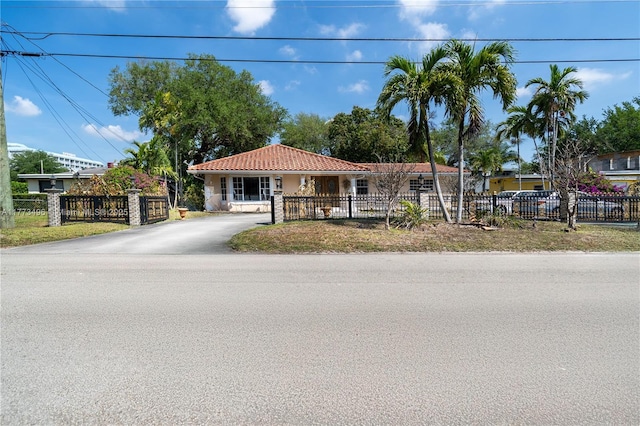 85 NW 165th St, Miami, FL 33169 - view of front facade featuring a tile roof, a fenced front yard, stucco siding, and driveway