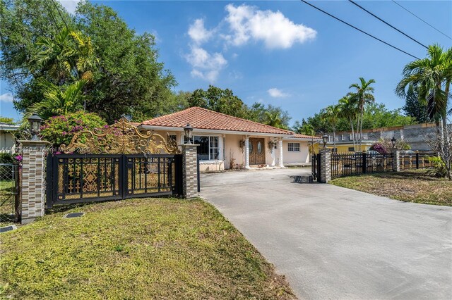 85 NW 165th St, Miami, FL 33169 - mediterranean / spanish home featuring a tile roof, concrete driveway, stucco siding, a fenced front yard, and a front lawn