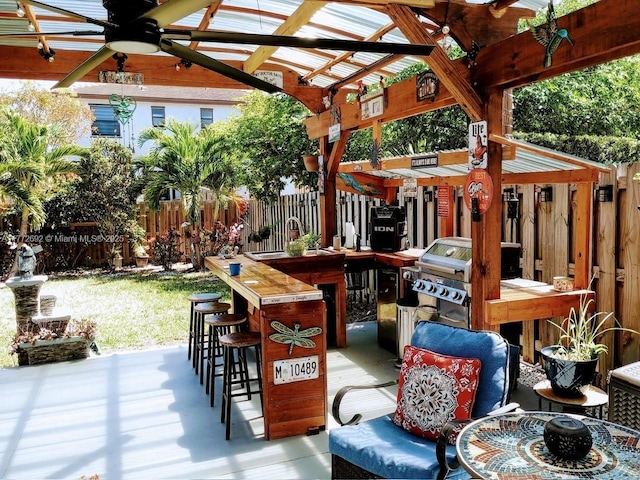 view of patio with a grill, fence, ceiling fan, and outdoor dry bar