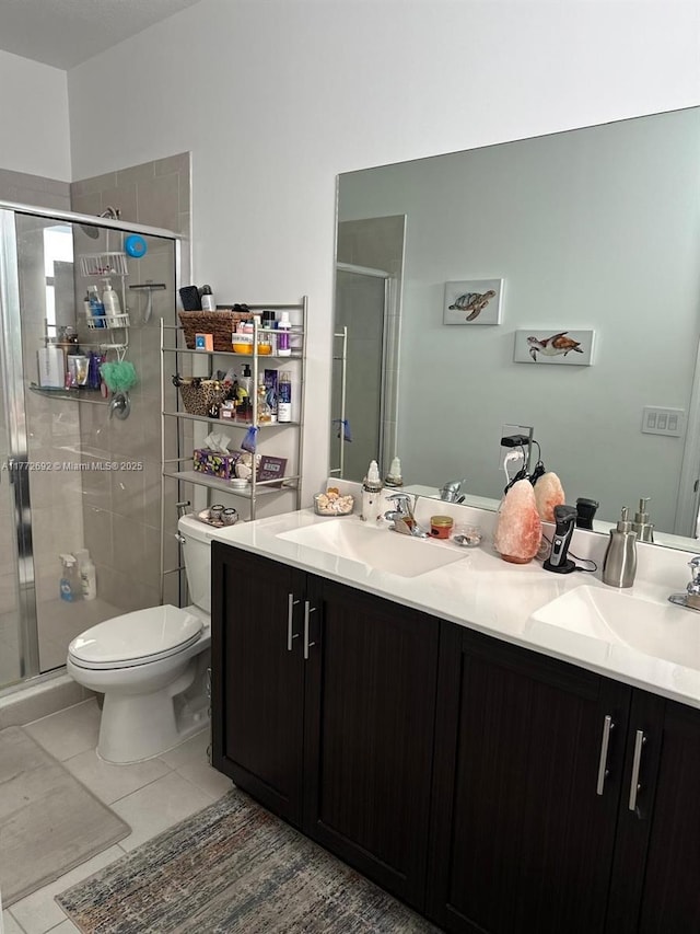 full bath featuring double vanity, a sink, toilet, and a shower stall