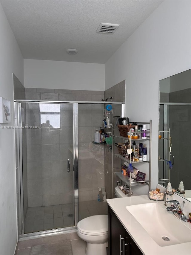 full bath featuring toilet, vanity, a shower stall, and visible vents