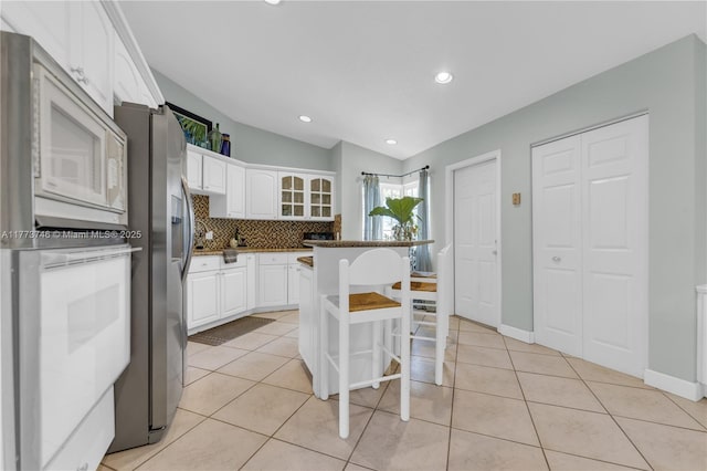 13878 SW 151st Ln, Miami, FL 33186 - kitchen featuring a breakfast bar, white microwave, stainless steel fridge, white cabinetry, and tasteful backsplash