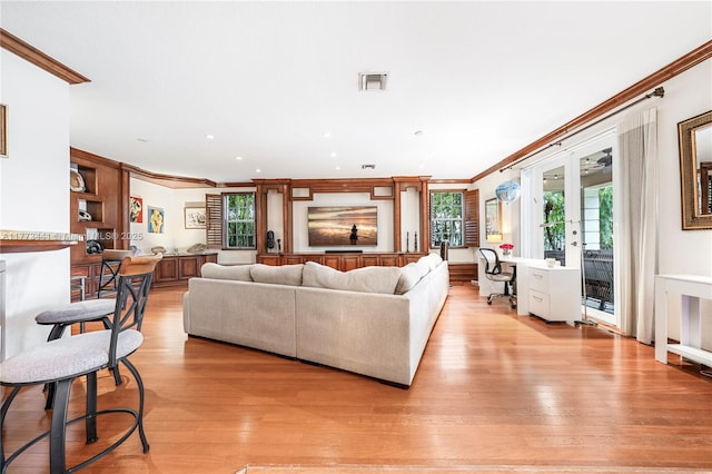 living room with light wood-style flooring, visible vents, and ornamental molding