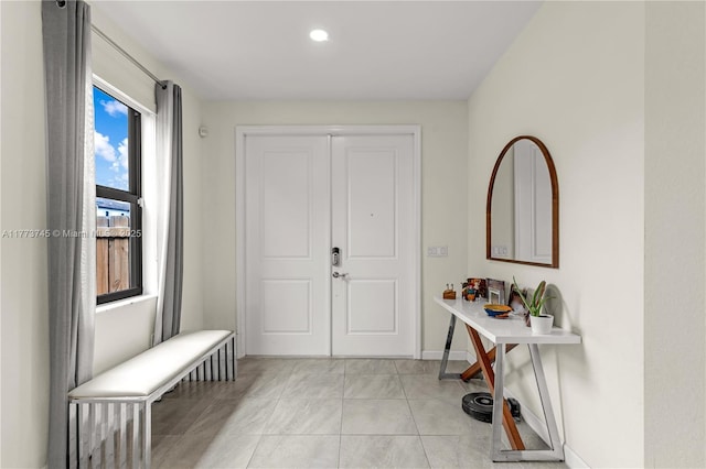 entryway with baseboards and light tile patterned floors
