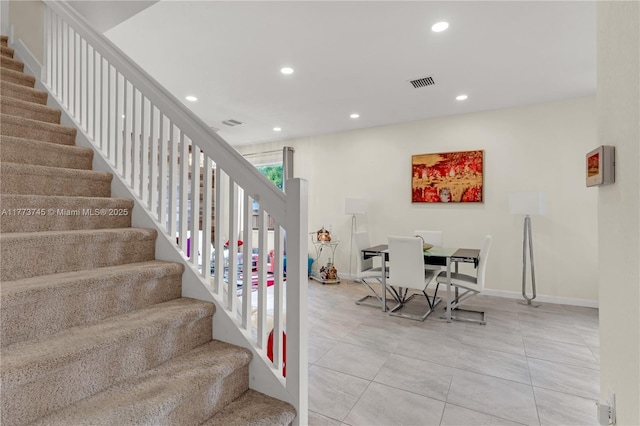 stairway featuring baseboards, visible vents, tile patterned flooring, and recessed lighting