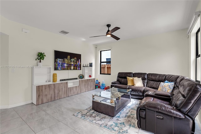 living area with baseboards, visible vents, light tile patterned floors, and a ceiling fan
