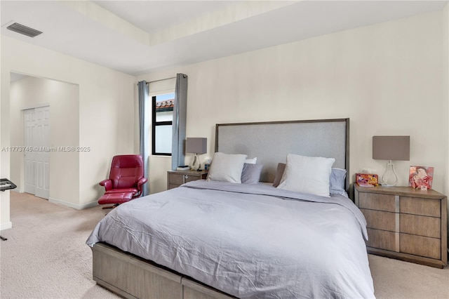 carpeted bedroom featuring baseboards, a tray ceiling, and visible vents