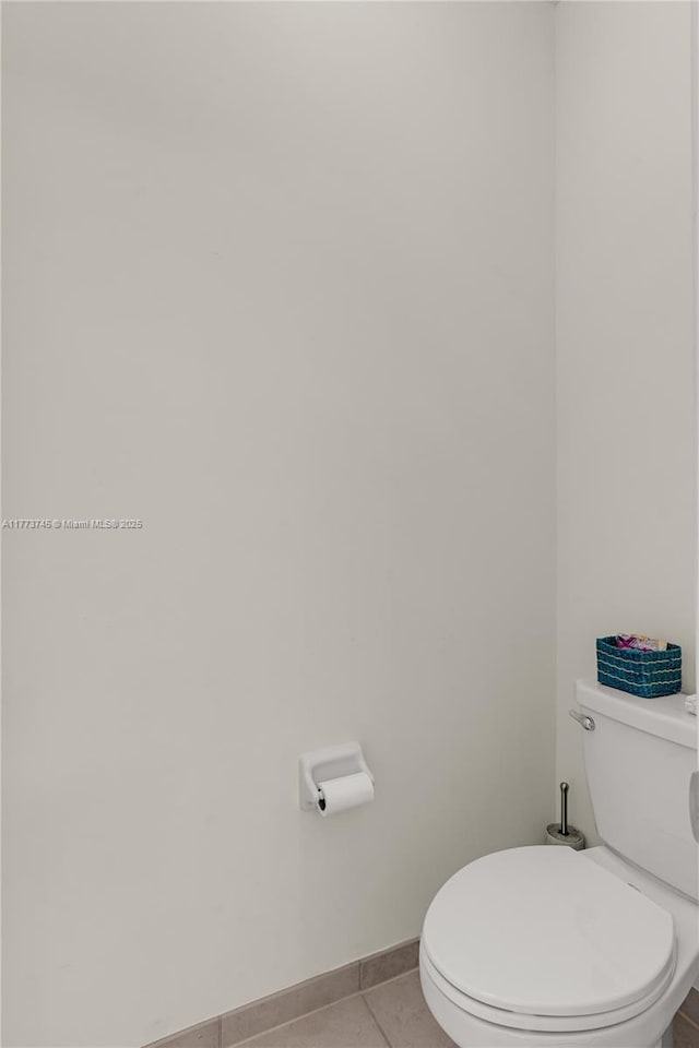 bathroom with tile patterned floors, toilet, and baseboards
