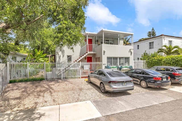 view of front of house featuring stucco siding, stairs, and fence