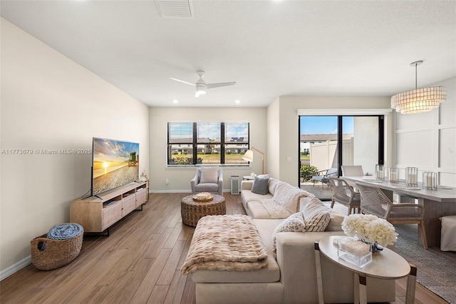 living area with baseboards, ceiling fan, visible vents, and light wood-type flooring