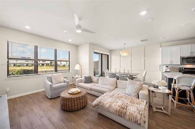 living room with a textured ceiling, baseboards, ceiling fan, wood finished floors, and recessed lighting