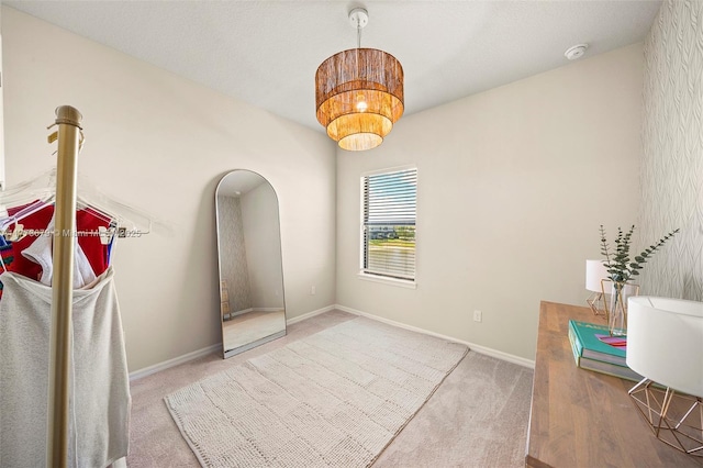 interior space with a notable chandelier, carpet, and baseboards