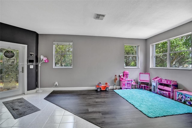 playroom featuring baseboards, visible vents, and a textured ceiling