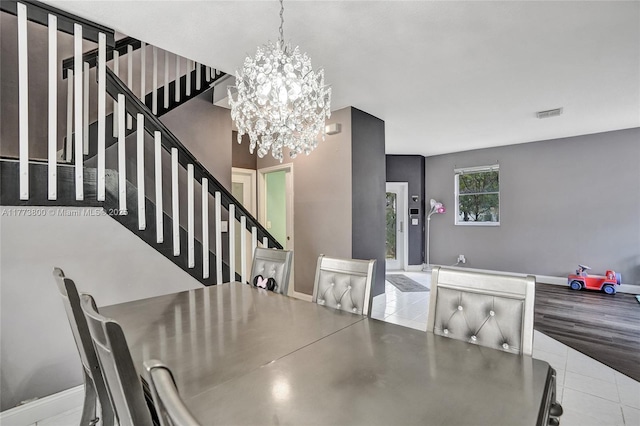 dining area featuring a notable chandelier, baseboards, stairs, and visible vents