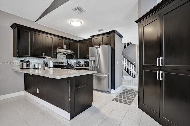 kitchen featuring backsplash, under cabinet range hood, appliances with stainless steel finishes, and a peninsula