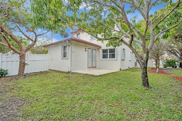 back of house with stucco siding, fence, a patio, french doors, and a lawn