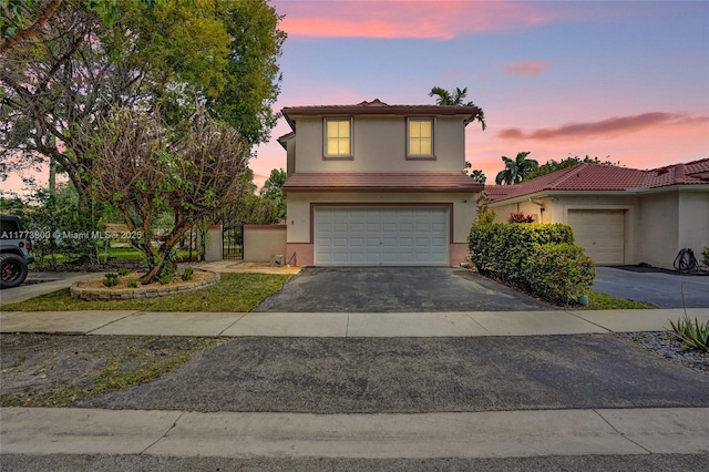 traditional-style house with stucco siding, aphalt driveway, a garage, and a tiled roof
