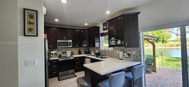 kitchen with light countertops, a peninsula, backsplash, and stainless steel appliances