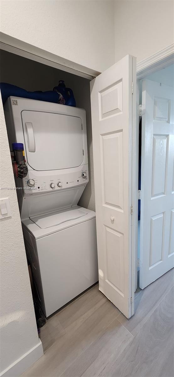 washroom with stacked washer and dryer, light wood-style floors, and laundry area