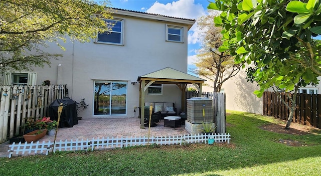 back of property with a patio, a fenced backyard, a gazebo, stucco siding, and a lawn