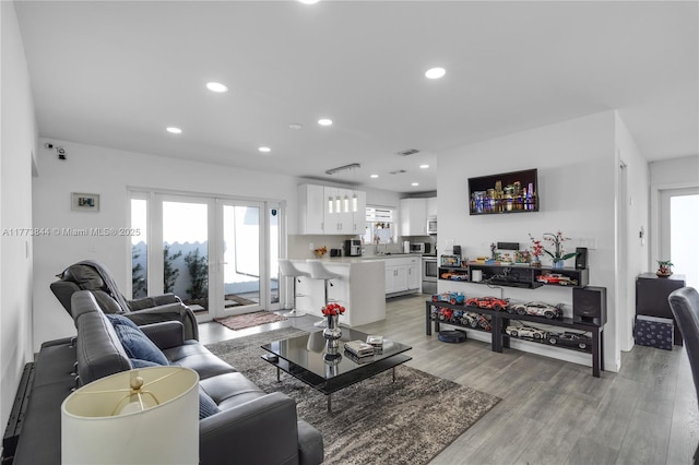 living room featuring light wood-type flooring, visible vents, and recessed lighting