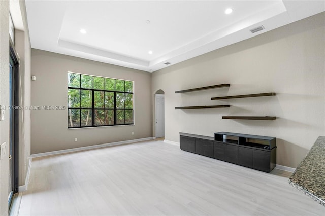 2031 SW 185th Ave, Miramar, FL 33029 - unfurnished living room featuring a tray ceiling, light wood-style floors, arched walkways, and recessed lighting