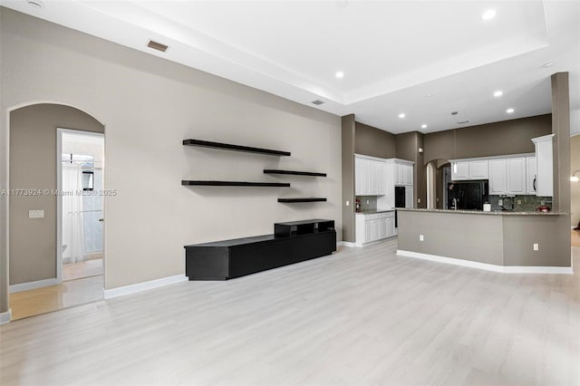 2031 SW 185th Ave, Miramar, FL 33029 - unfurnished living room with arched walkways, light wood-style floors, recessed lighting, and a tray ceiling
