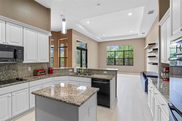 2031 SW 185th Ave, Miramar, FL 33029 - kitchen featuring black appliances, a raised ceiling, a peninsula, light wood-type flooring, and backsplash