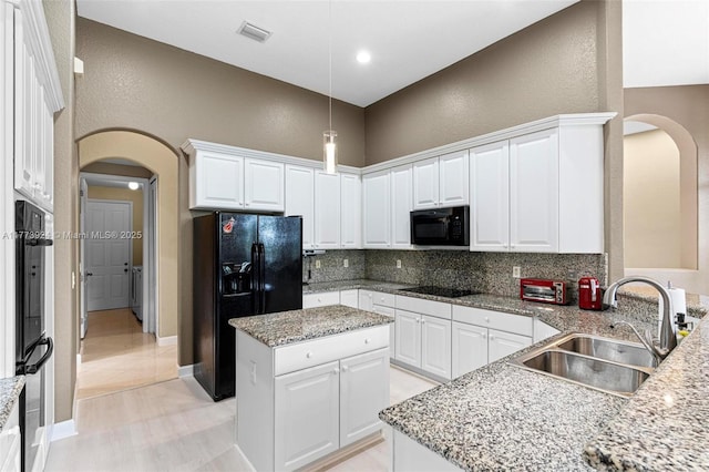 2031 SW 185th Ave, Miramar, FL 33029 - kitchen featuring black appliances, arched walkways, decorative backsplash, a textured wall, and white cabinetry
