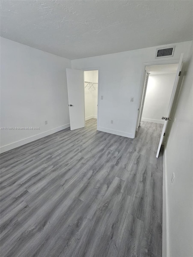 empty room with visible vents, baseboards, wood finished floors, and a textured ceiling