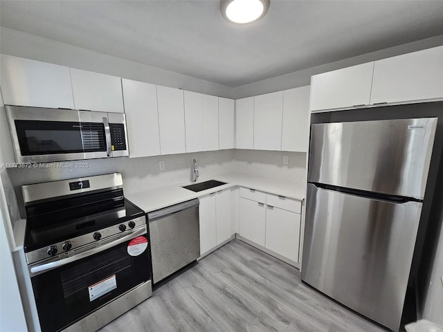 kitchen featuring a sink, light countertops, white cabinets, and stainless steel appliances