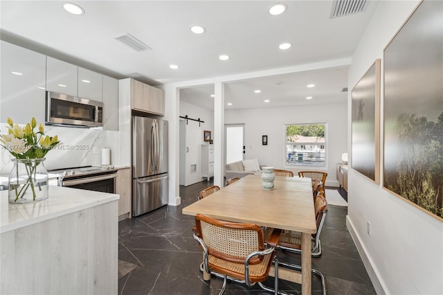 dining area featuring baseboards, visible vents, a barn door, and recessed lighting