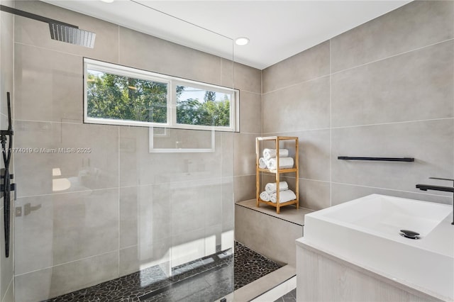 full bath with tile walls, a sink, and a walk in shower