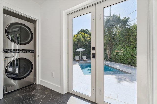 laundry area featuring laundry area, marble finish floor, baseboards, and stacked washing maching and dryer