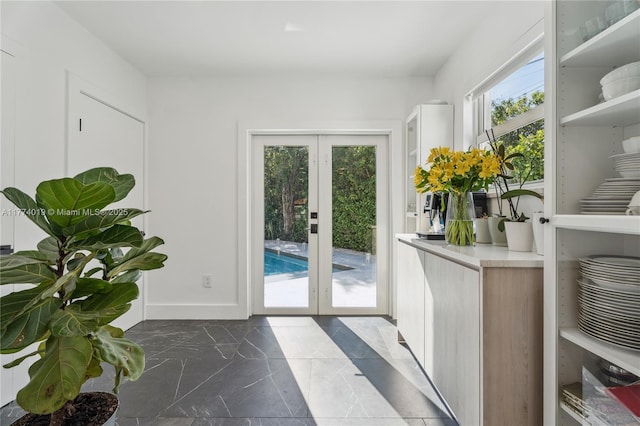 doorway to outside featuring baseboards, marble finish floor, and french doors
